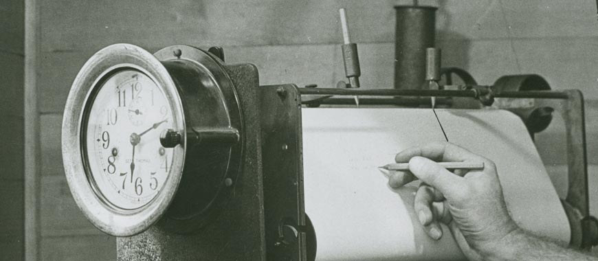 a seismograph with aosmebody writing on the drum cylinder 