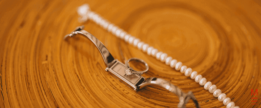 Watch, necklace and ring on a wooden table