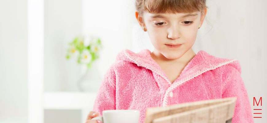 A young girl reading a newspaper