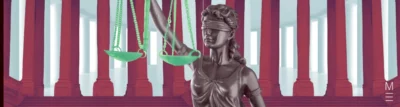 Lady Justice statue holding green scales against a background of red pillars