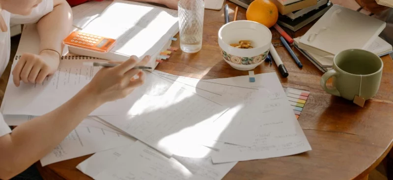 Students studying together with notes, a calculator, and snacks on a table.