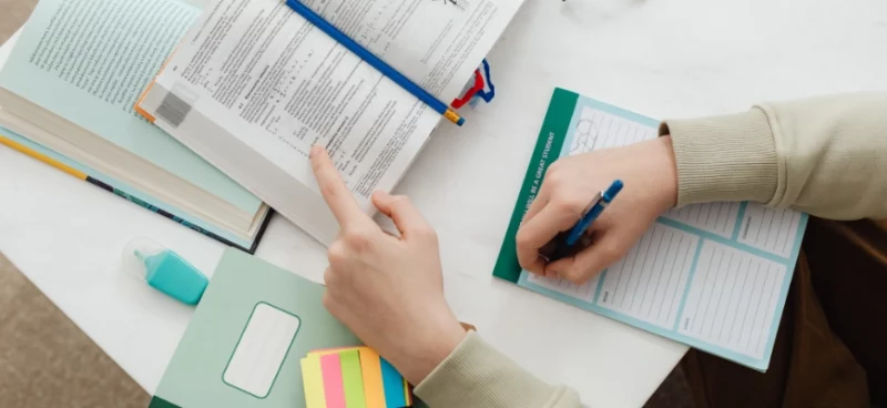 Student reviewing textbooks and taking notes with a planner