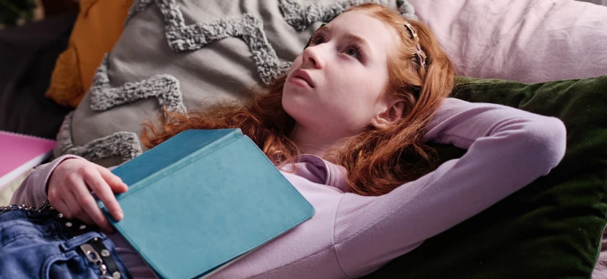 matrix education A teenage girl lying down with a book, looking thoughtful
