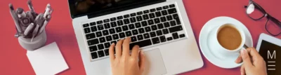 Workspace with a laptop, notebook, coffee, and tools on a red desk