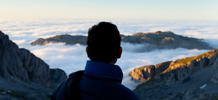 A person gazing at a scenic mountain landscape above the clouds