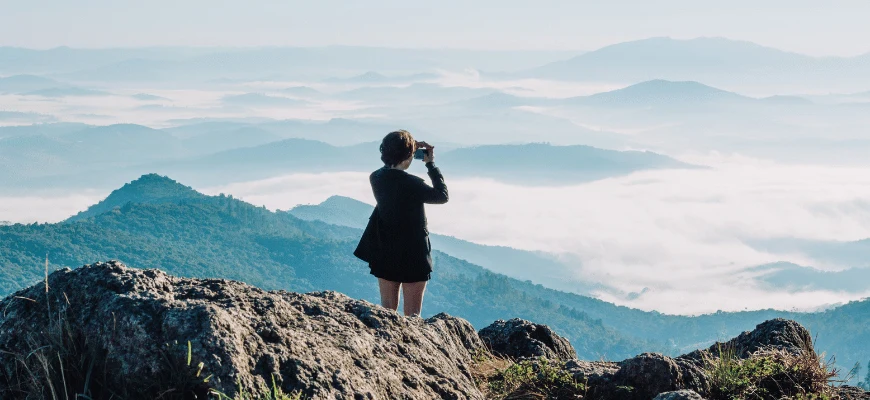 Person looking through binoculars at a mountain view