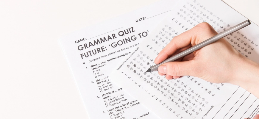 Hand filling out a multiple-choice grammar quiz on a test sheet