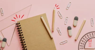 Notebook with pencils, erasers, ruler, and protractor on a pink background