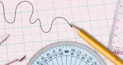 Graph paper with a pencil, protractor, and rulers for maths work