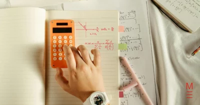 Student working on maths problems with a calculator and equations in a notebook