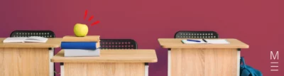 Wooden school desks with books, an apple, and stationery placed on top