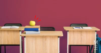 Wooden school desks with books, an apple, and stationery placed on top