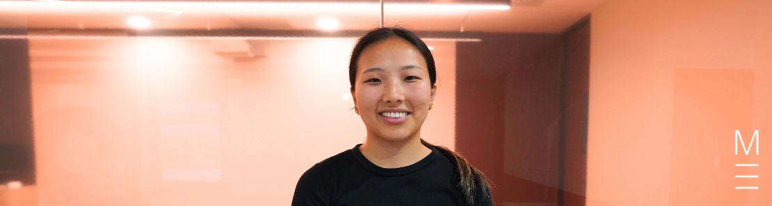Smiling young woman in a black t-shirt in a modern study space.