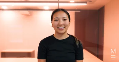 Smiling young woman in a black t-shirt in a modern study space.