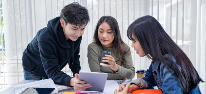 matrix education Three students studying together, looking at a tablet during holiday tutoring programs