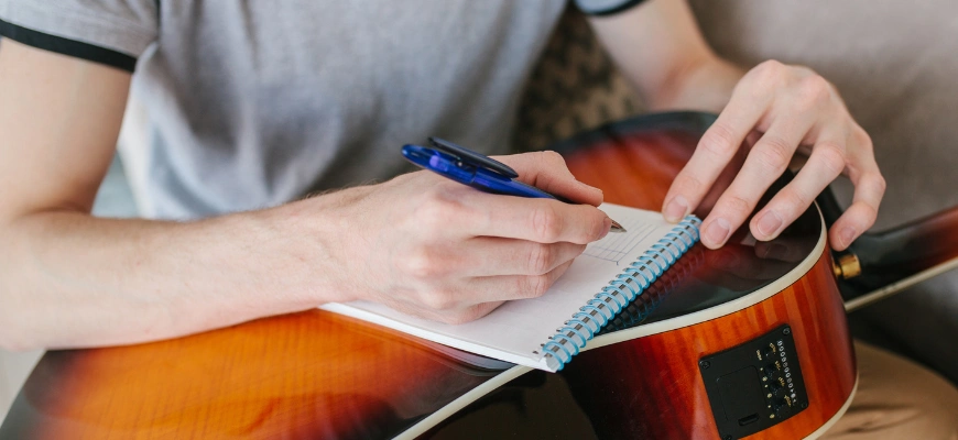 matrix education person writing in a notebook while holding a guitar symbolising benefits of holiday tutoring